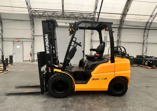 Side profile of a yellow and black Thompson Lift Truck forklift parked inside a warehouse on a concrete floor.