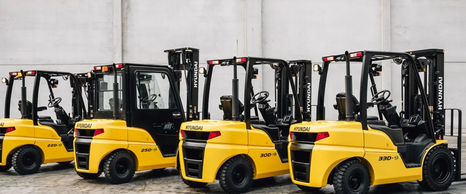 A lineup of several yellow and black Thompson Lift Truck forklifts parked neatly in a row inside warehouse.