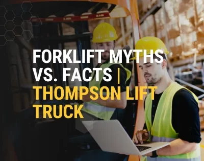 Warehouse workers reviewing data beside a forklift, addressing forklift myths and facts, forklift misconceptions