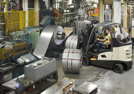 Thompson Lift Truck Crown forklift moving large metal coils in a manufacturing facility